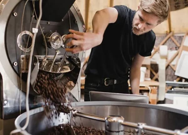 Coffee beans pouring from a roaster in a food production facility